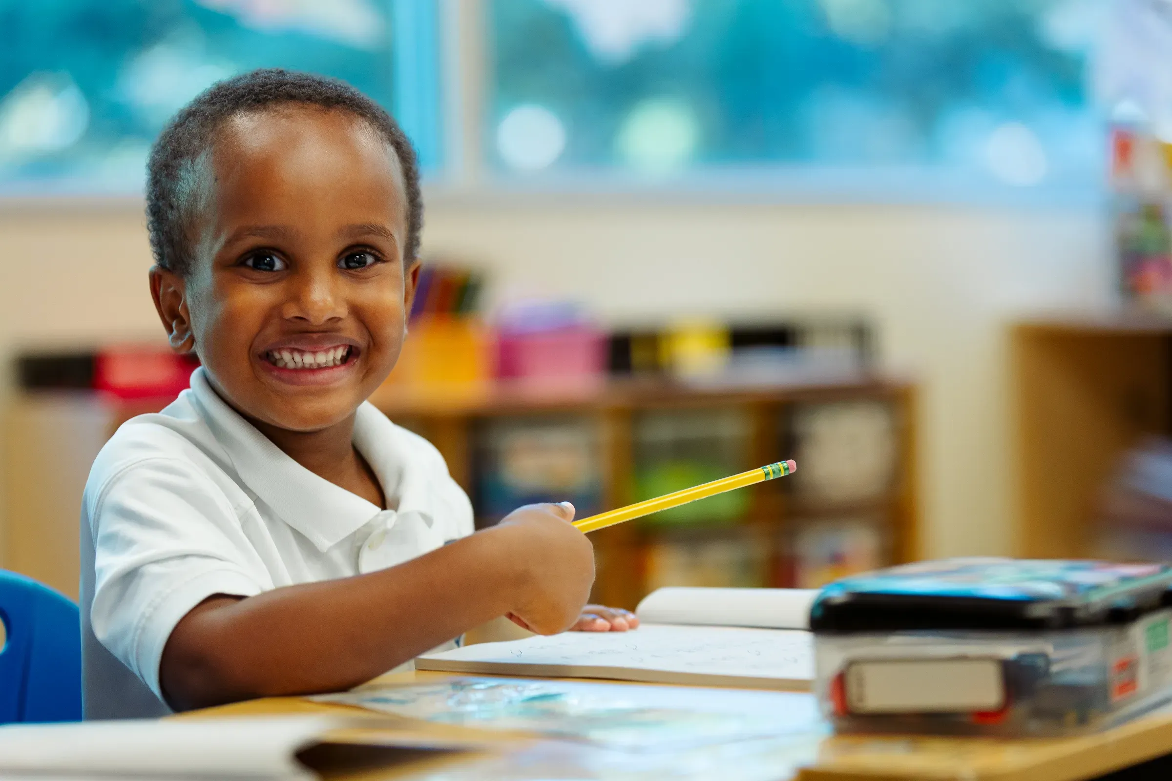 Preschooler smiling at the art table during a candid classroom session