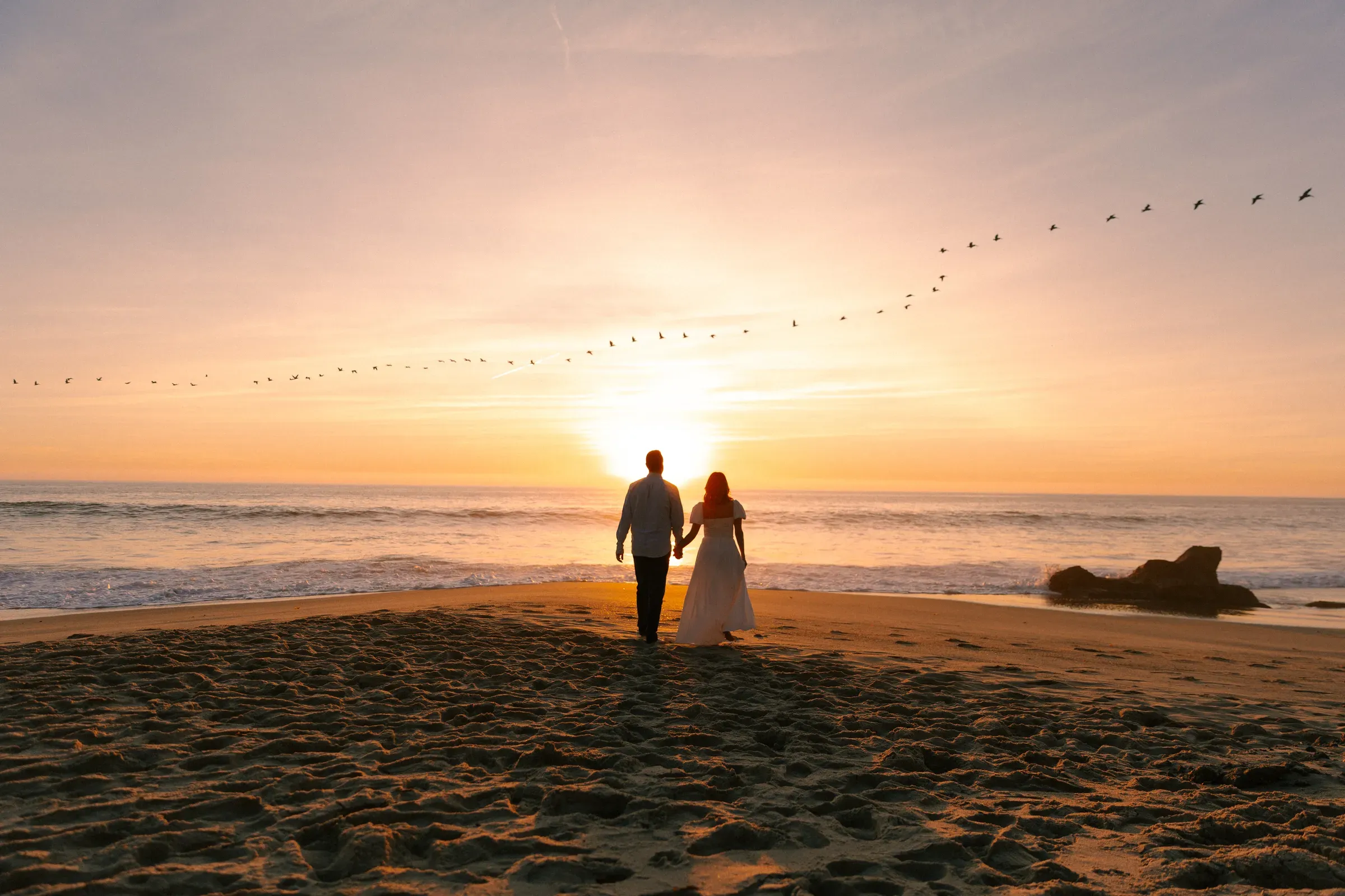 Engagement session — couple silhouetted against the ocean sunset