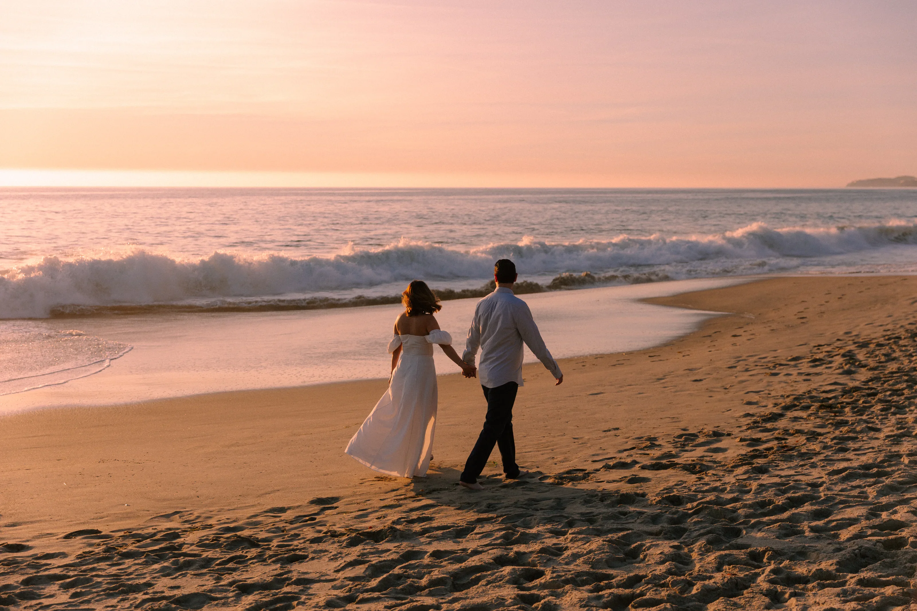 Couple walking the shoreline at sunset