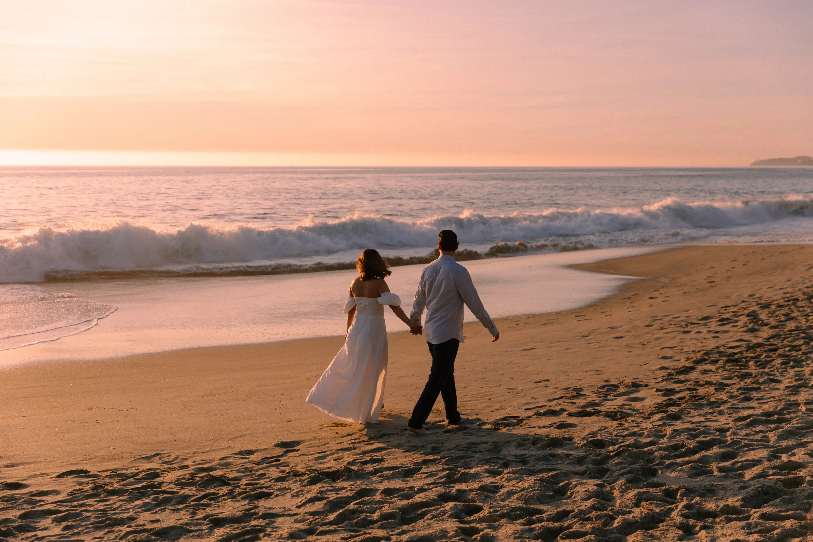 Couple walking the shoreline at sunset