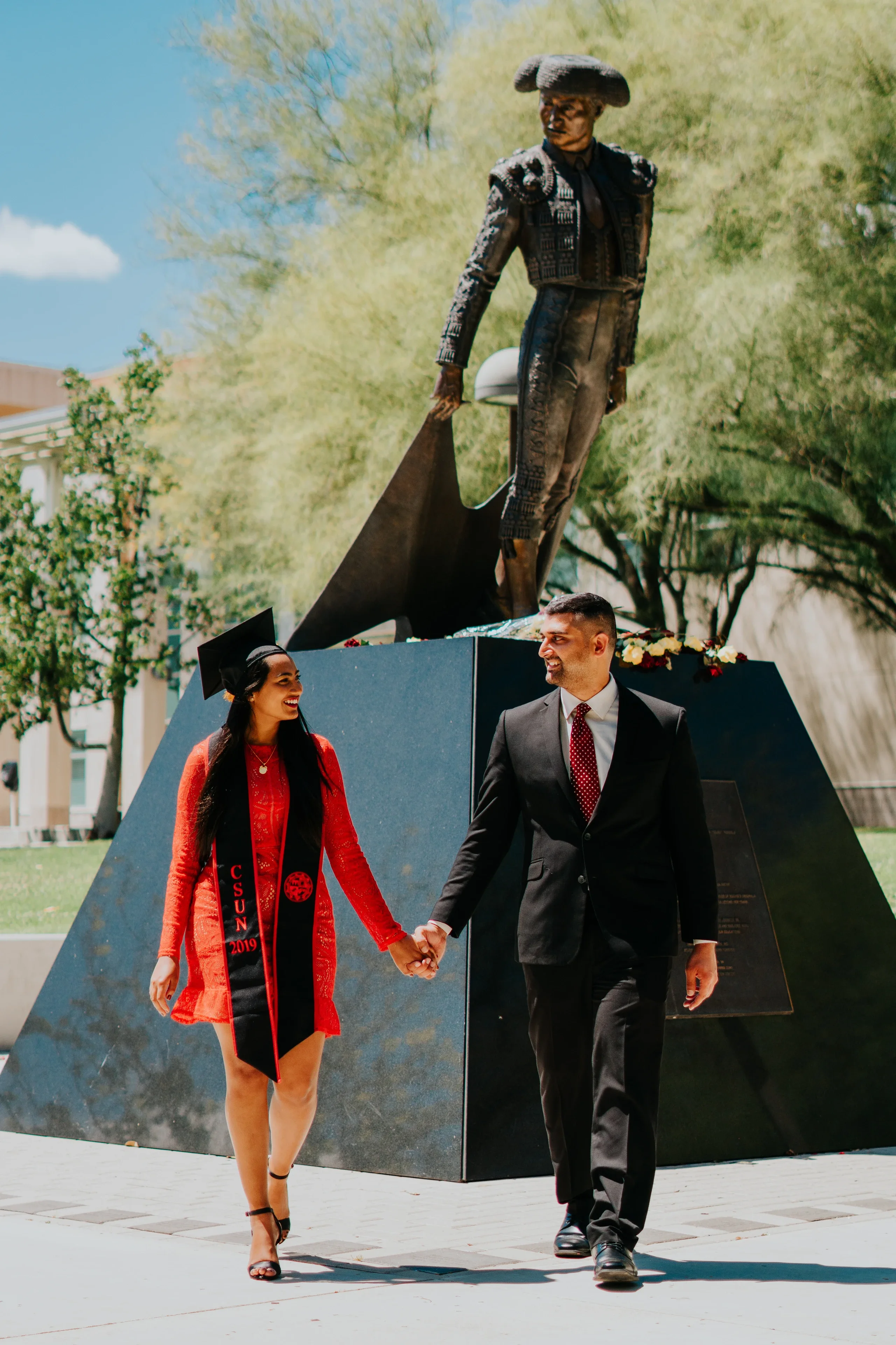 Two Cal State Fullerton graduates walking together in commencement attire