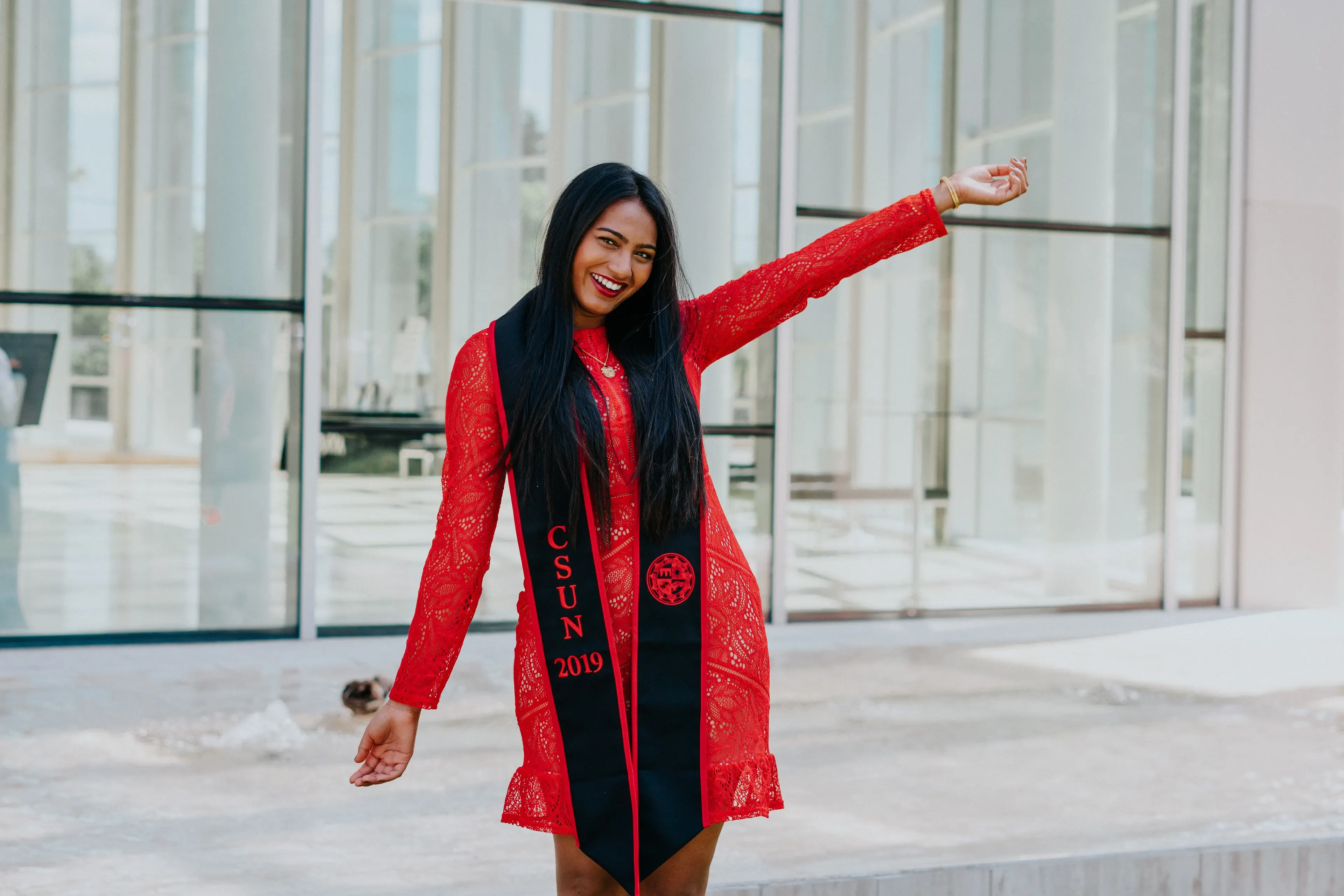 Cal State Fullerton graduate celebrating outside a modern campus building