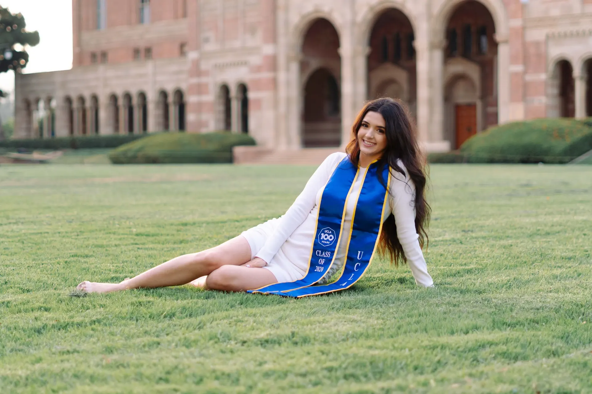 UCLA graduate reclining on the lawn in front of Royce Hall