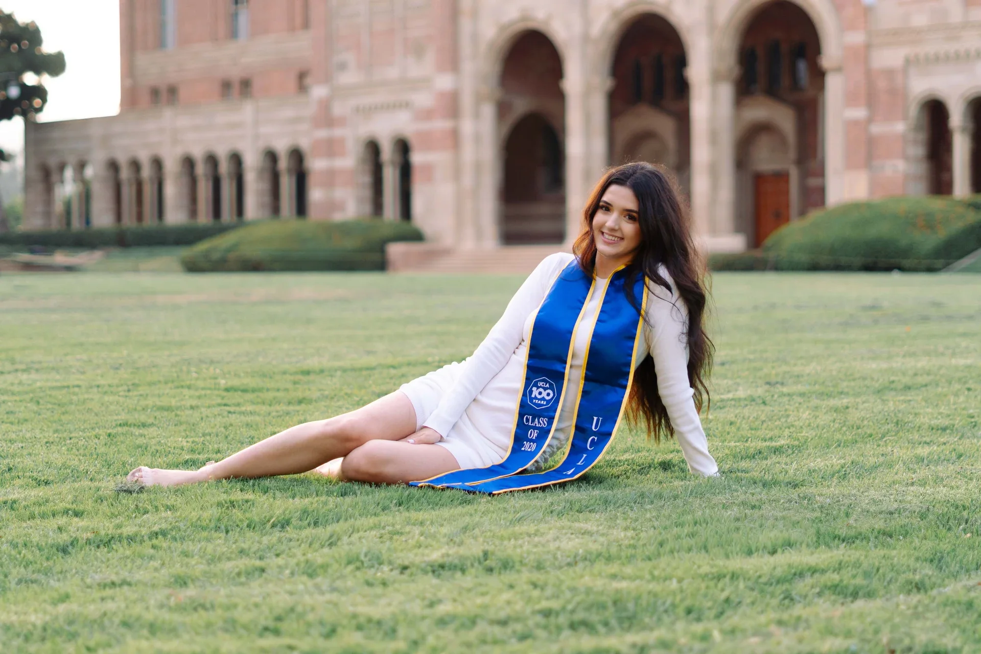 UCLA graduate reclining on the lawn in front of Royce Hall