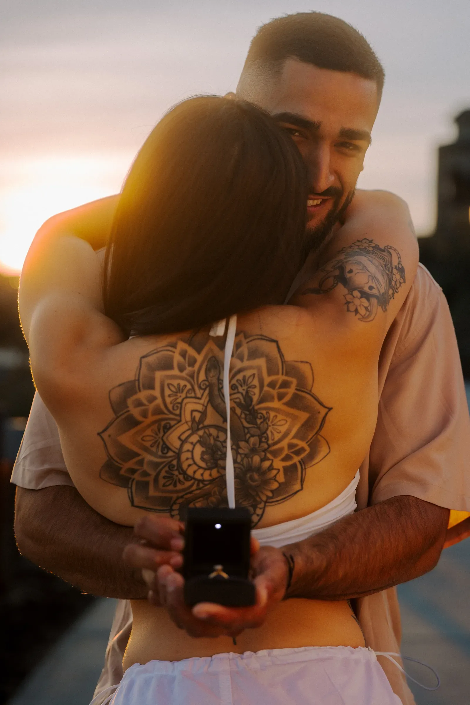 Couple embracing, tattooed arms holding close at sunset
