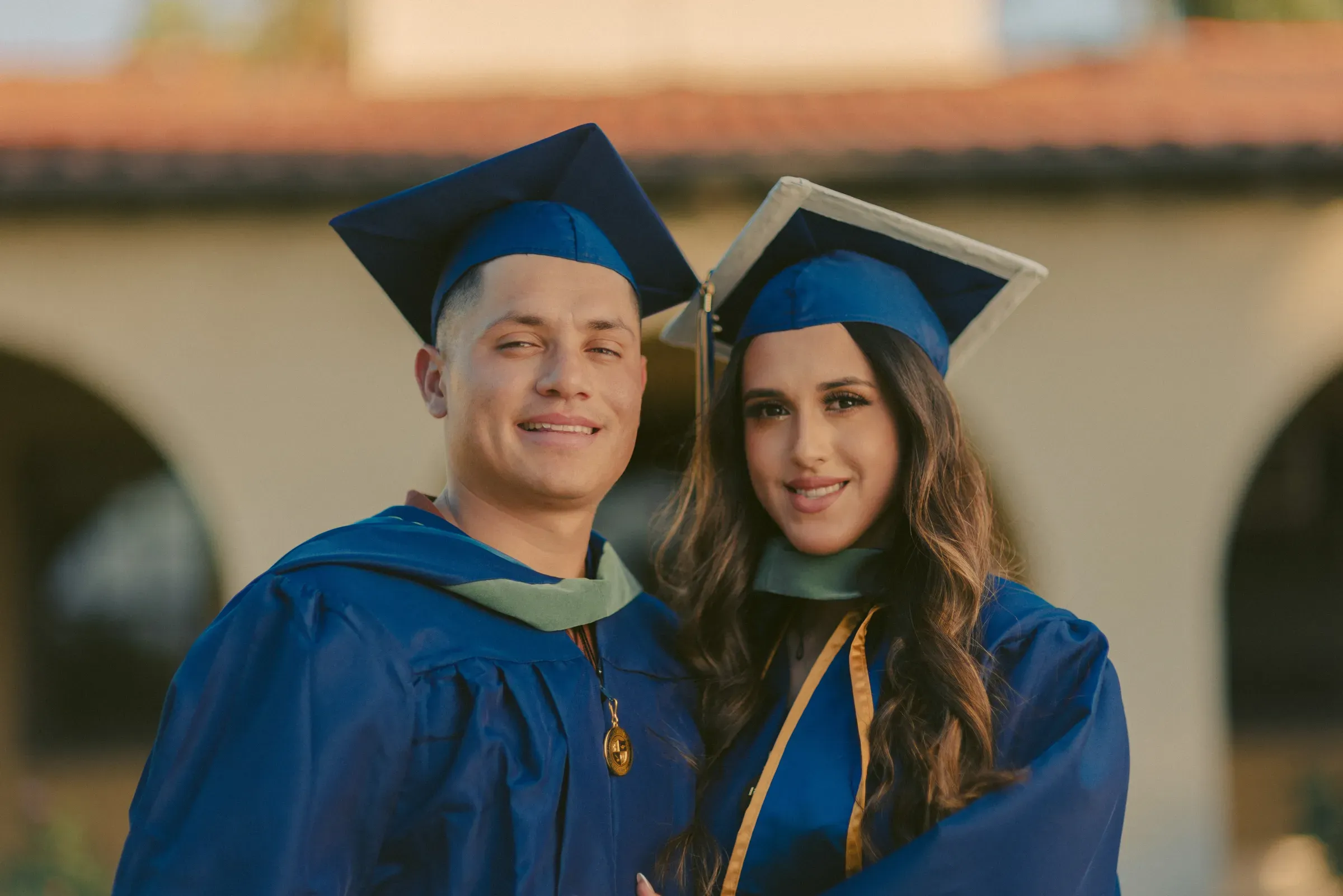 Two graduates in caps and gowns sharing the moment