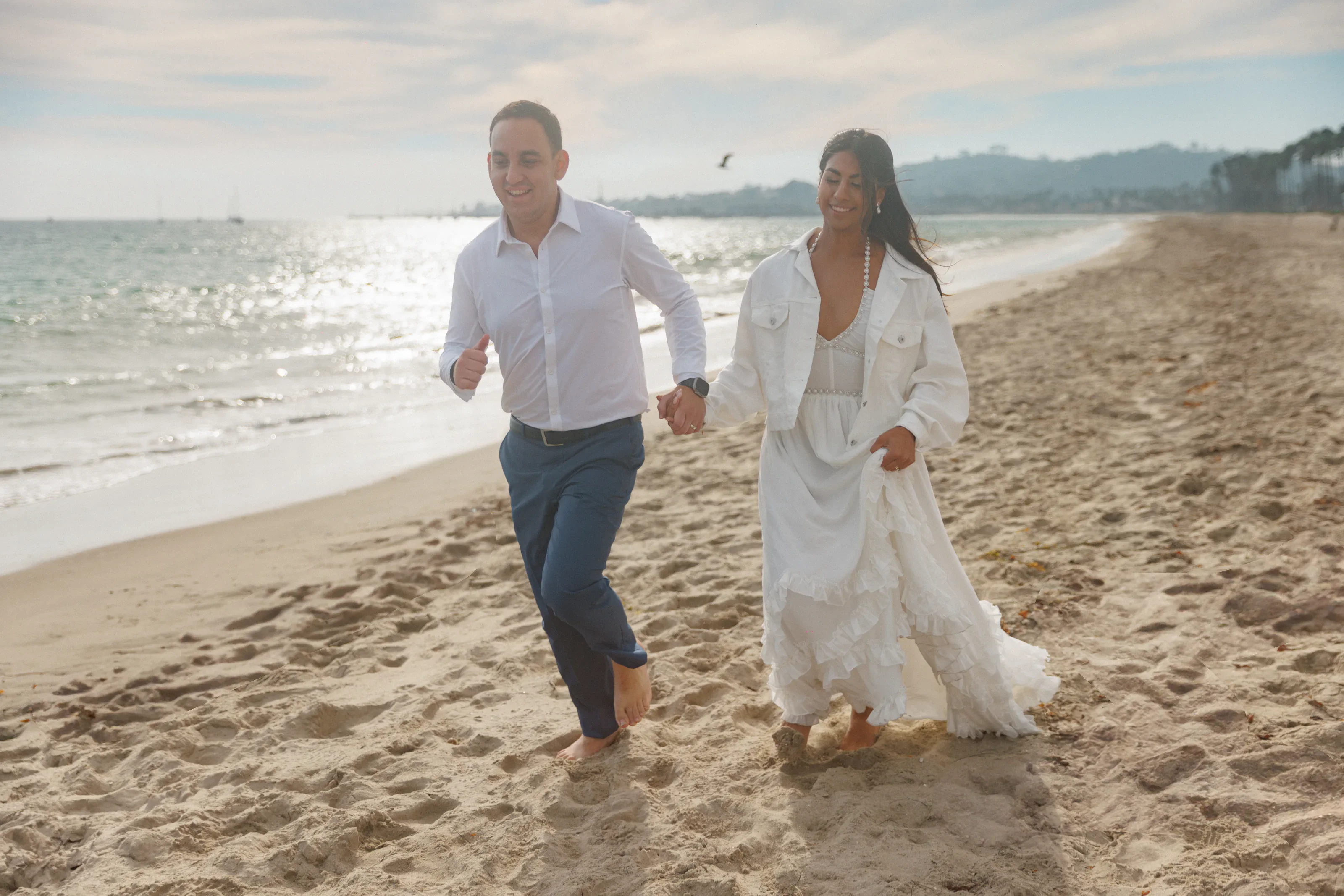 The newlyweds walking together along the Southern California shoreline